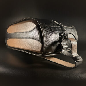 Luxury handstitched black and taupe leather messenger carryall bag with flowing curved design of handles and strap three quarter view of front and side