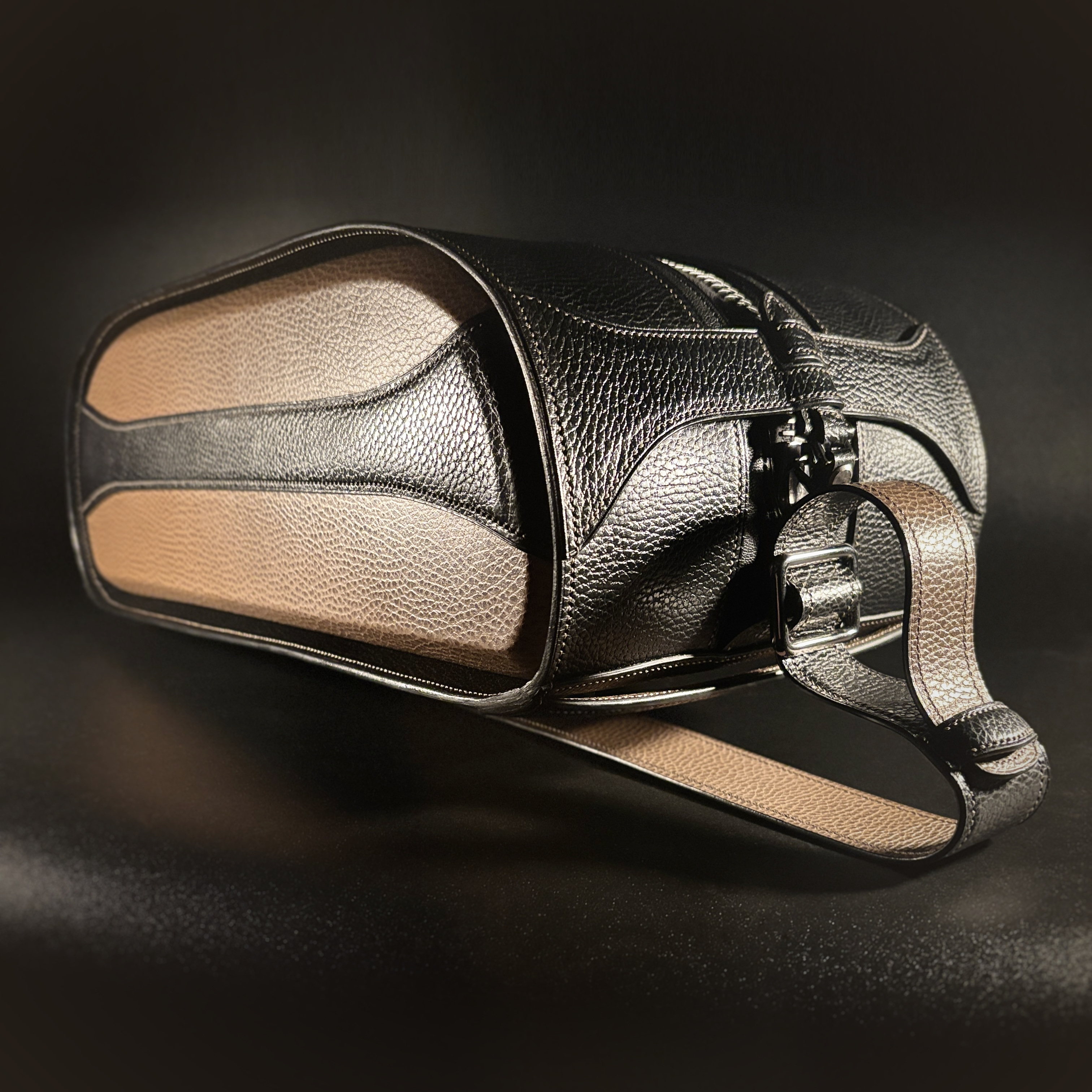 Luxury handstitched black and taupe leather messenger carryall bag with flowing curved design of handles and strap three quarter view of front and side