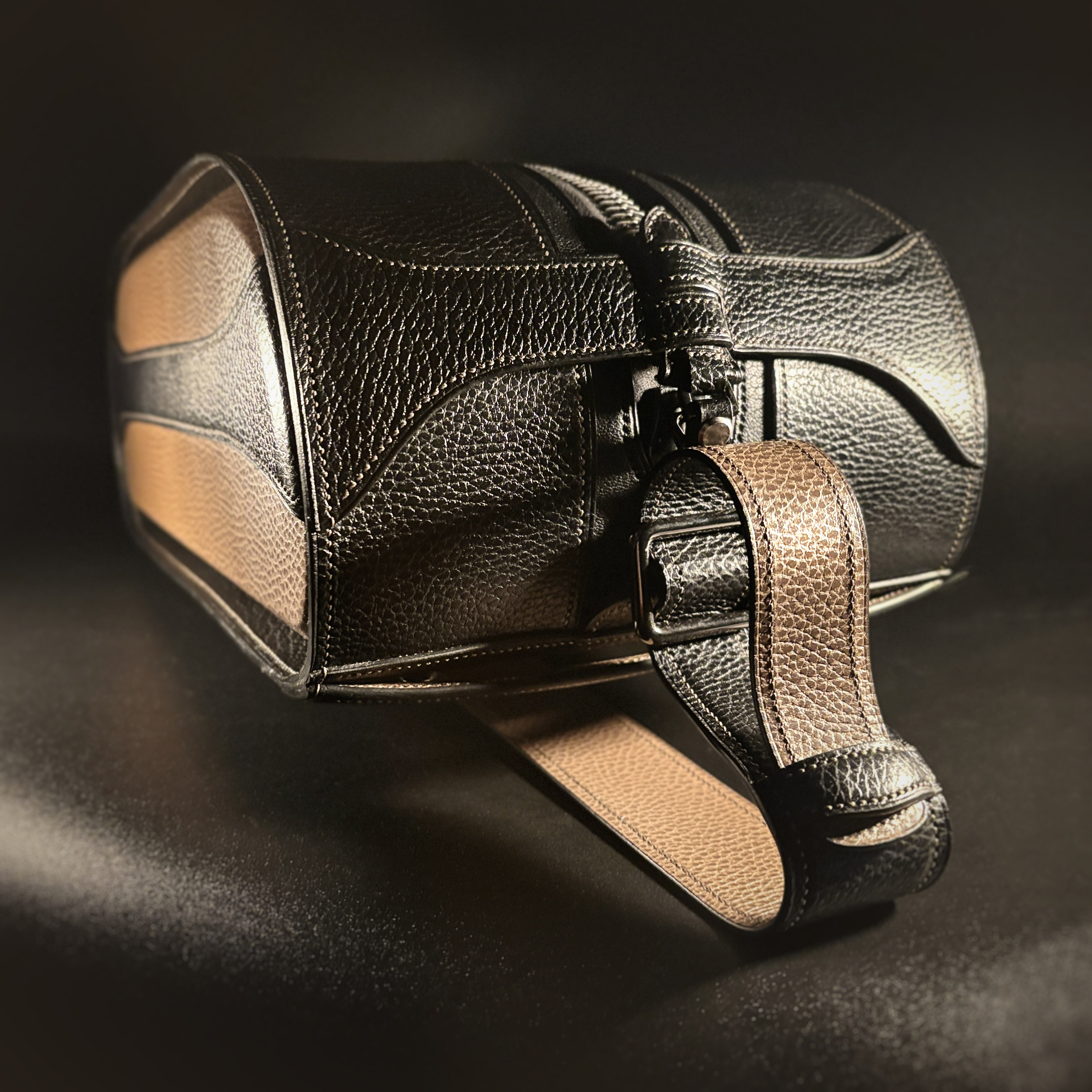 Luxury handstitched black and taupe leather messenger carryall bag with flowing curved design of handles and strap view of front with crossbody strap attached