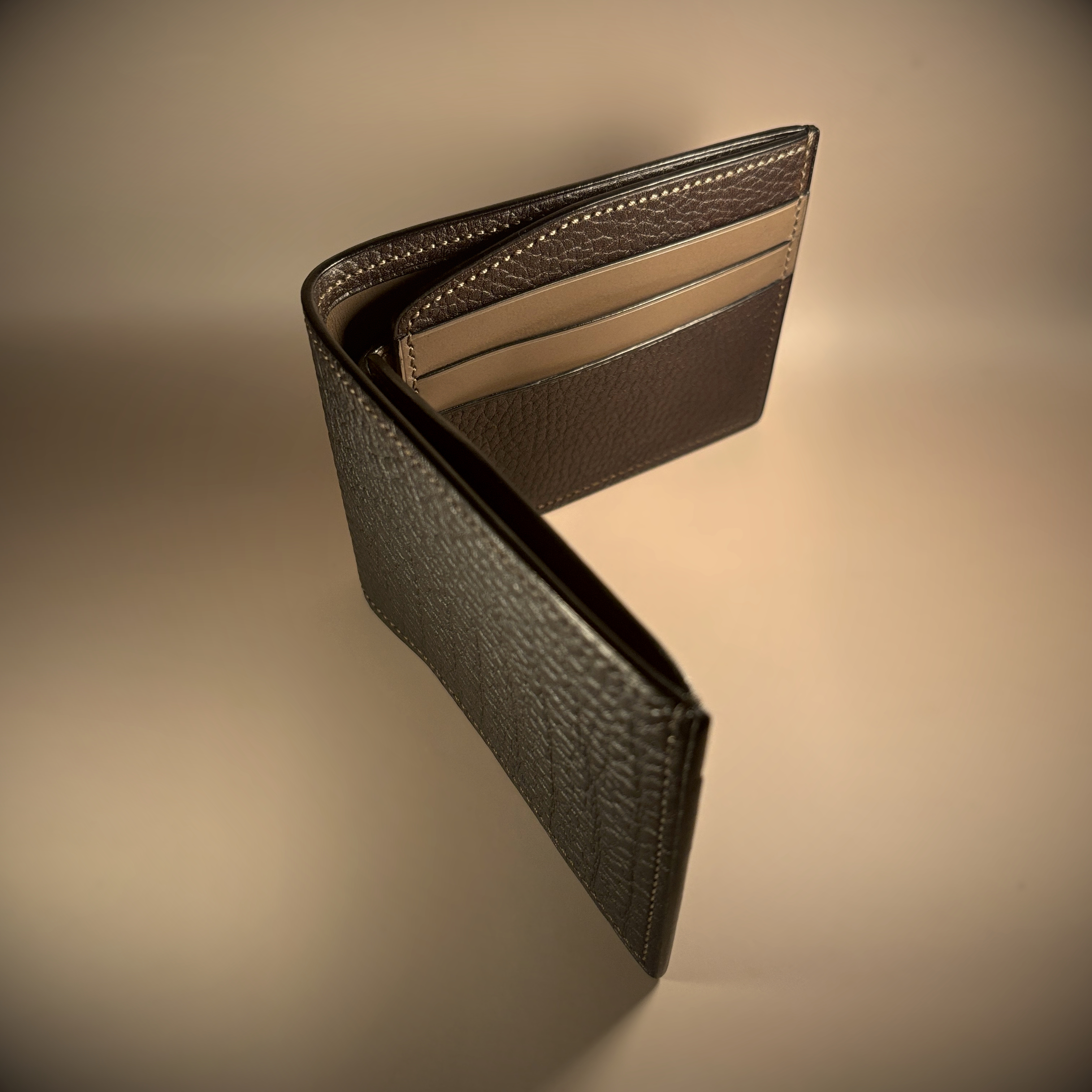 Unique handstitched textured dark brown shell and textured and smooth brown and taupe interior bifold wallet side view