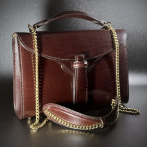 Unique handstitched mahogany brown and taupe tuck closure handbag purse brass chain shoulder strap and brass harware exterior shell front view
