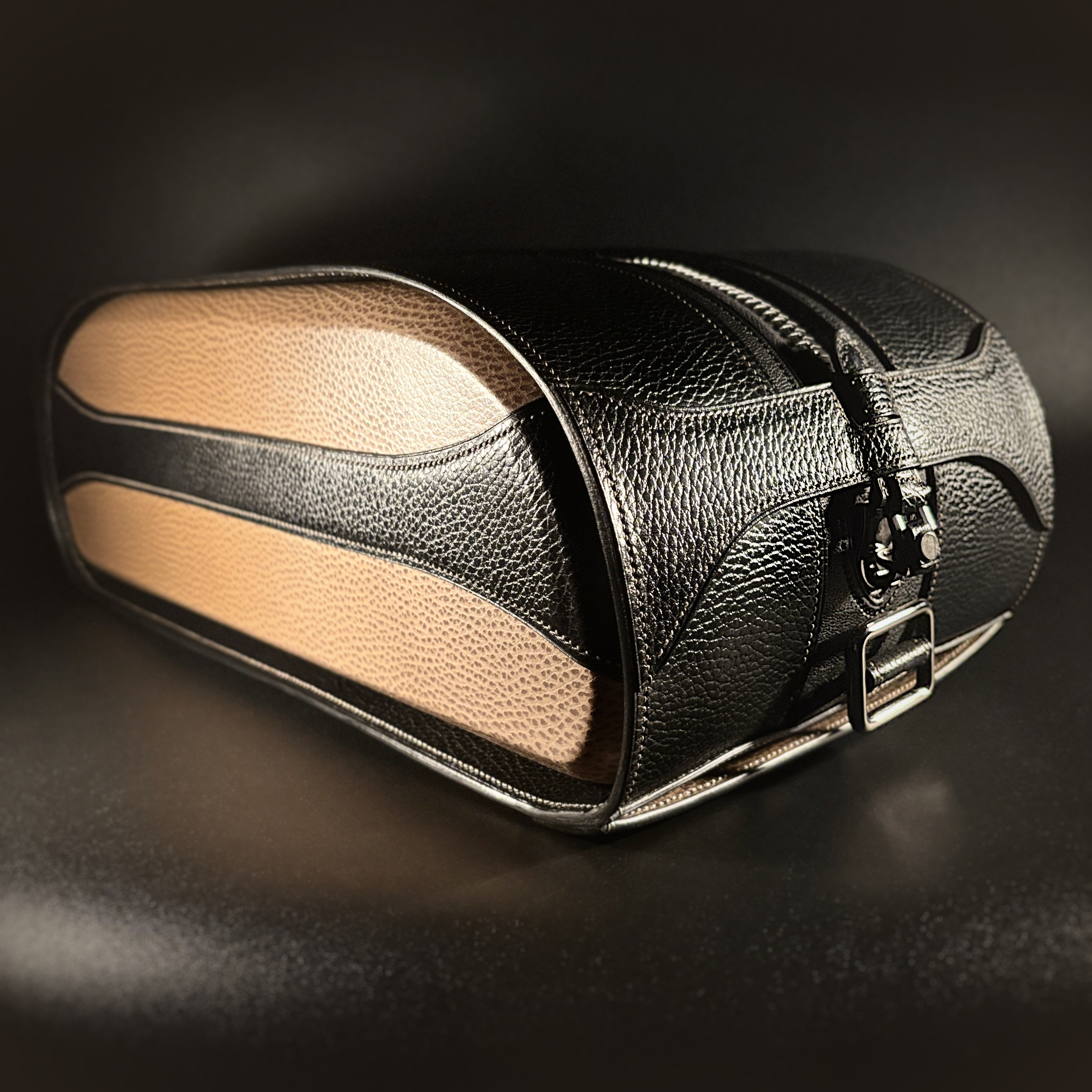 Luxury handstitched black and taupe leather messenger carryall bag with flowing curved design of handles and strap view of front and side with crossbody strap detached