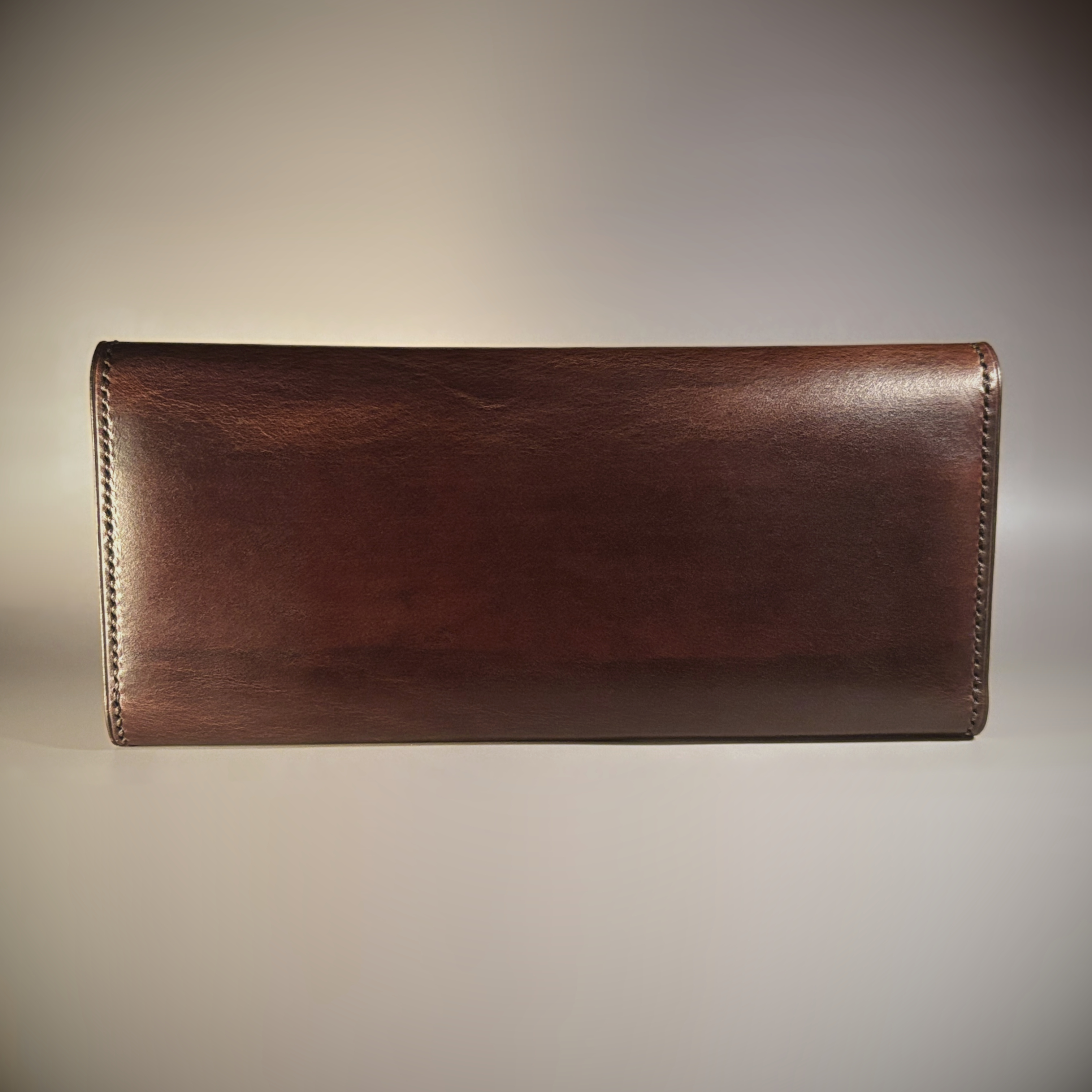 Unique handstitched tuck closure walnut shell and black and brown textured curved interior long wallet exterior rear view