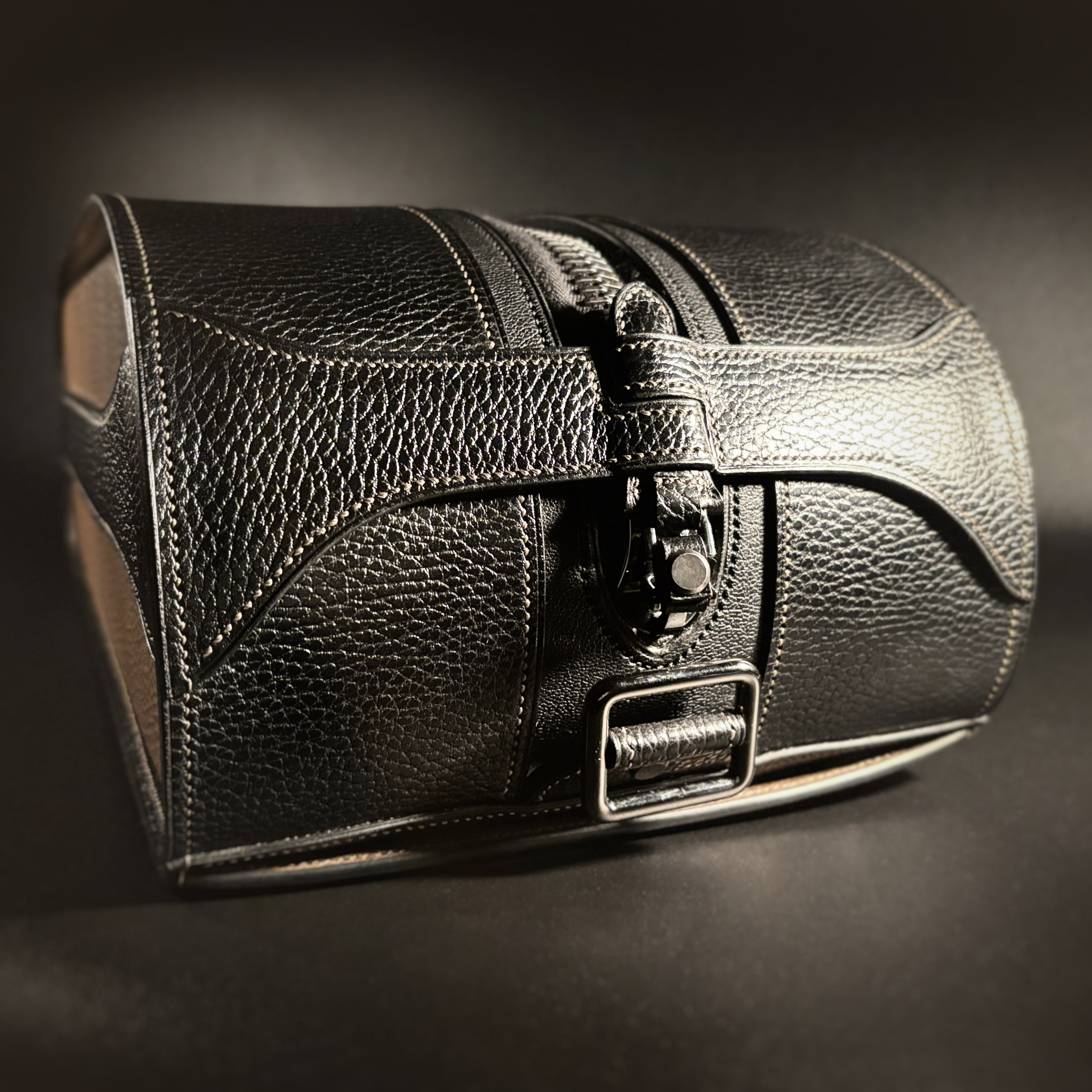 Luxury handstitched black and taupe leather messenger carryall bag with flowing curved design of handles and strap view of front with crossbody strap detached