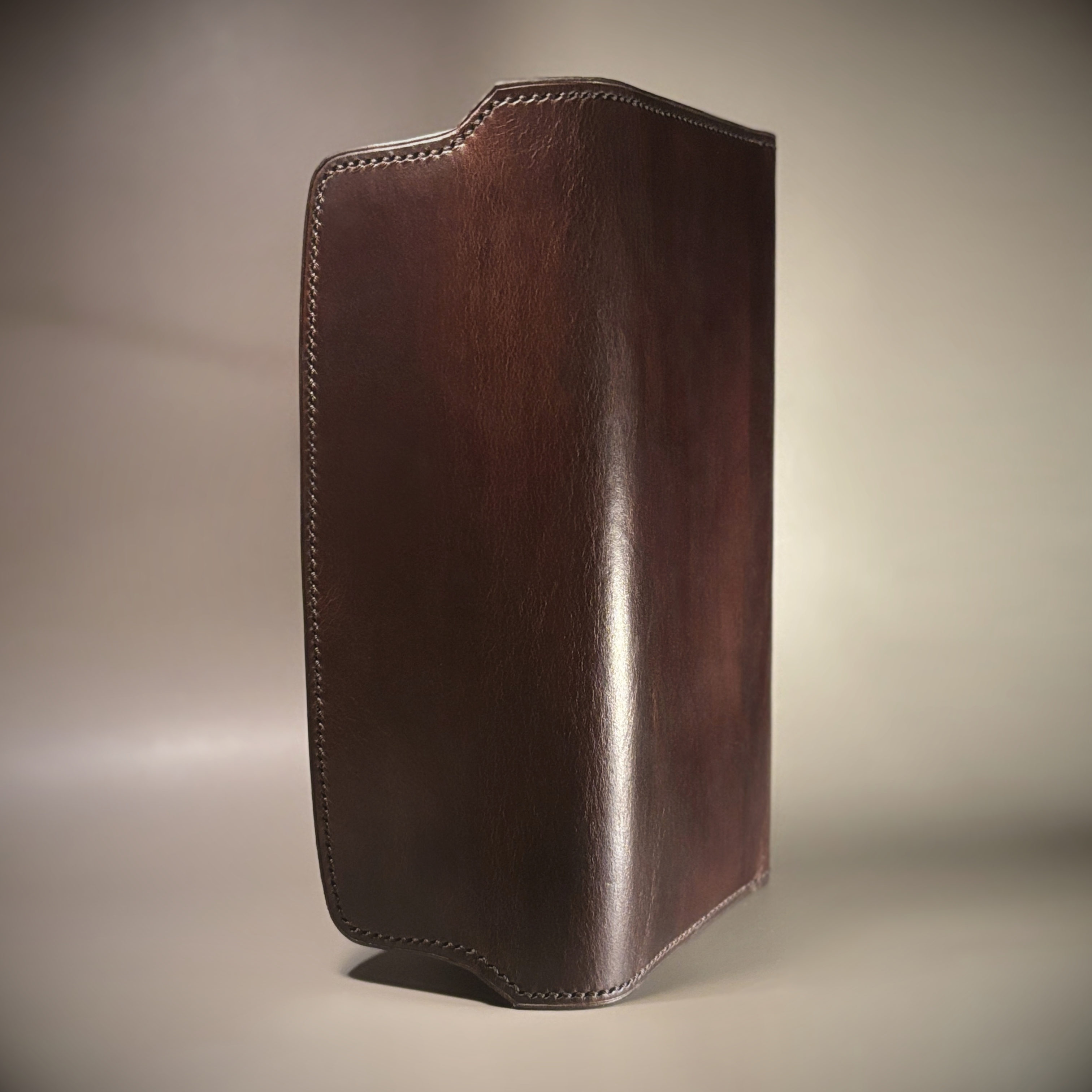 Unique handstitched tuck closure walnut shell and black and brown textured curved interior long wallet exterior vertical view