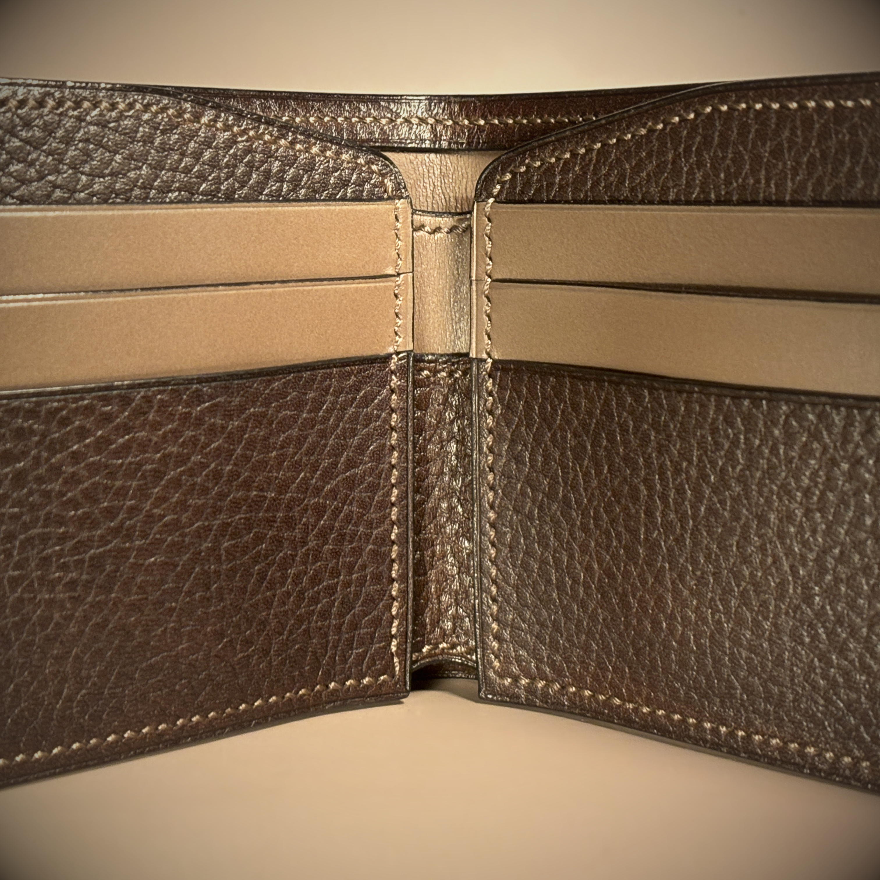 Unique handstitched textured dark brown shell and textured and smooth brown and taupe interior bifold wallet interior detail view