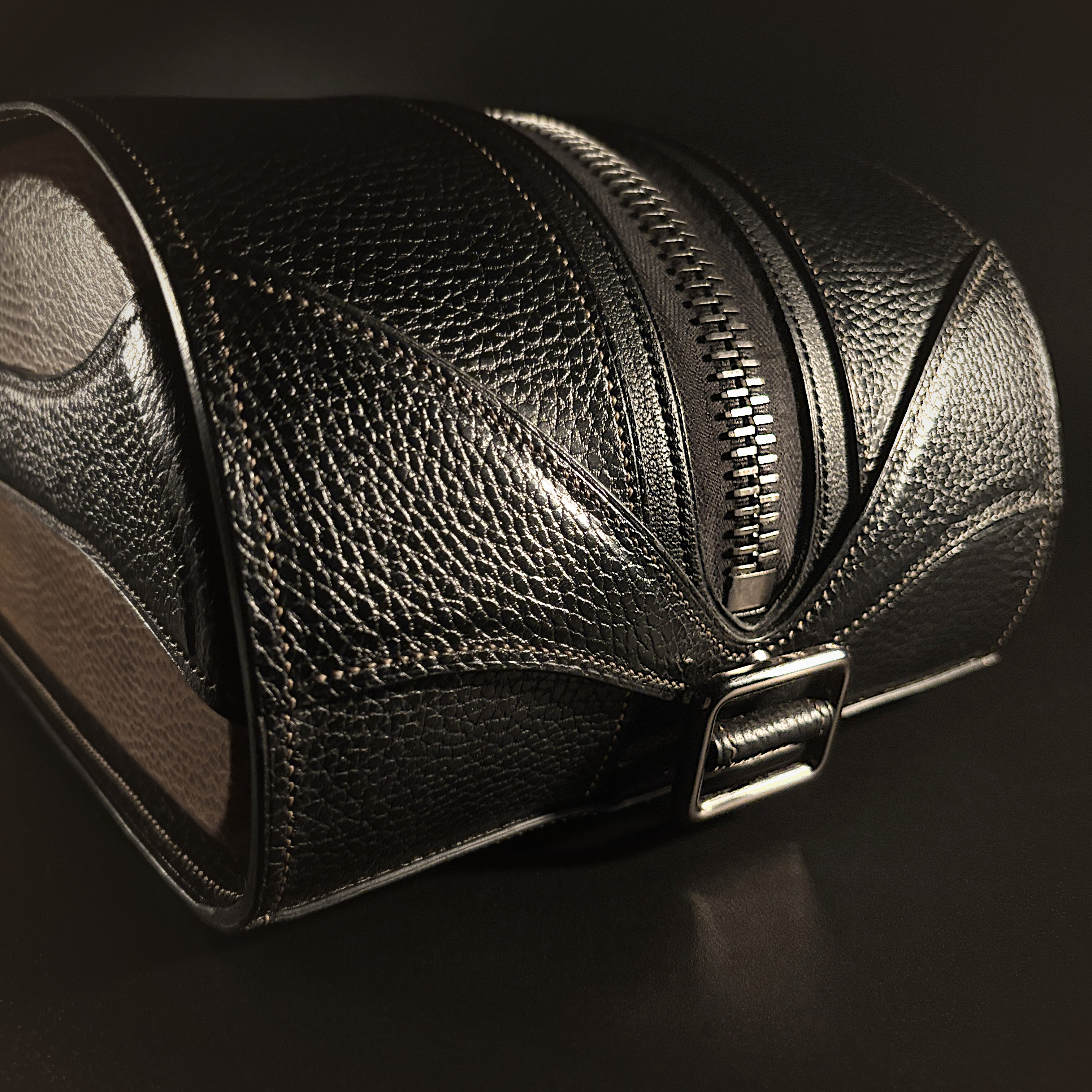 Luxury handstitched black and taupe leather messenger carryall bag with flowing curved design of handles and strap view of back with crossbody strap detached