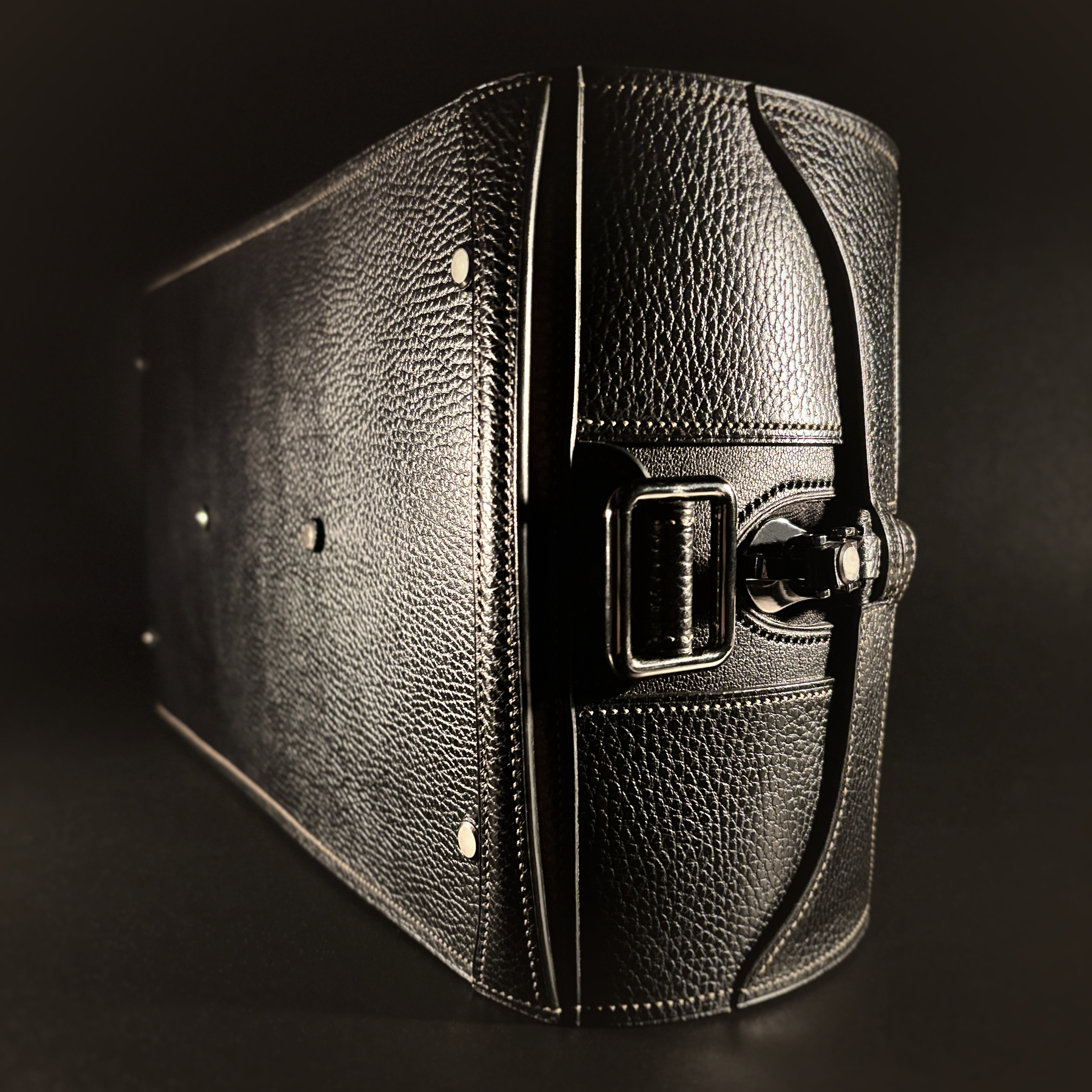 Luxury handstitched black and taupe leather messenger carryall bag with flowing curved design of handles and strap view of bottom feet and hand-carry handle with crossbody strap detached