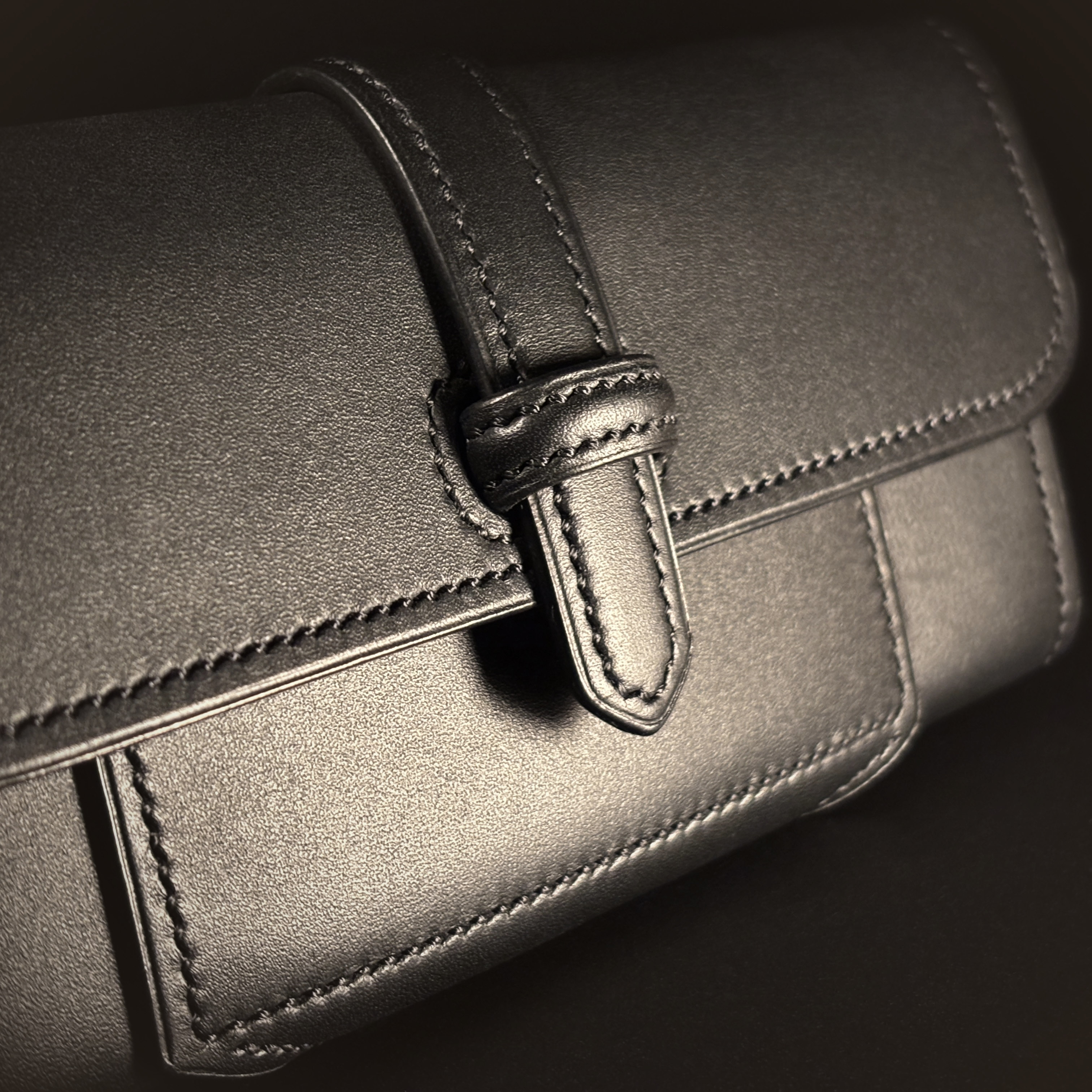 Luxury handstitched matte black clutch purse with unique tab closure detailed view of front tab closure