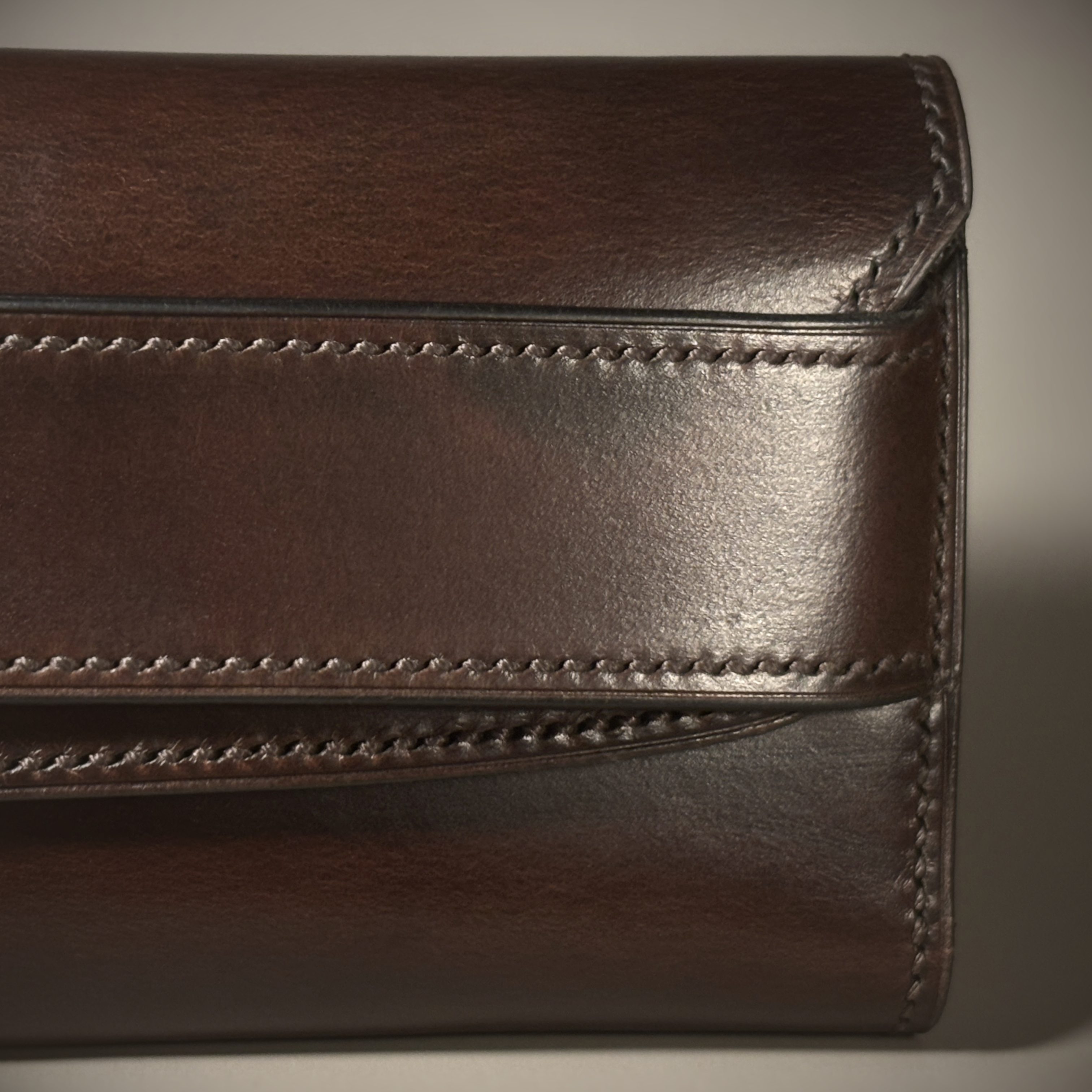 Unique handstitched tuck closure walnut shell and black and brown textured curved interior long wallet detailed exterior view