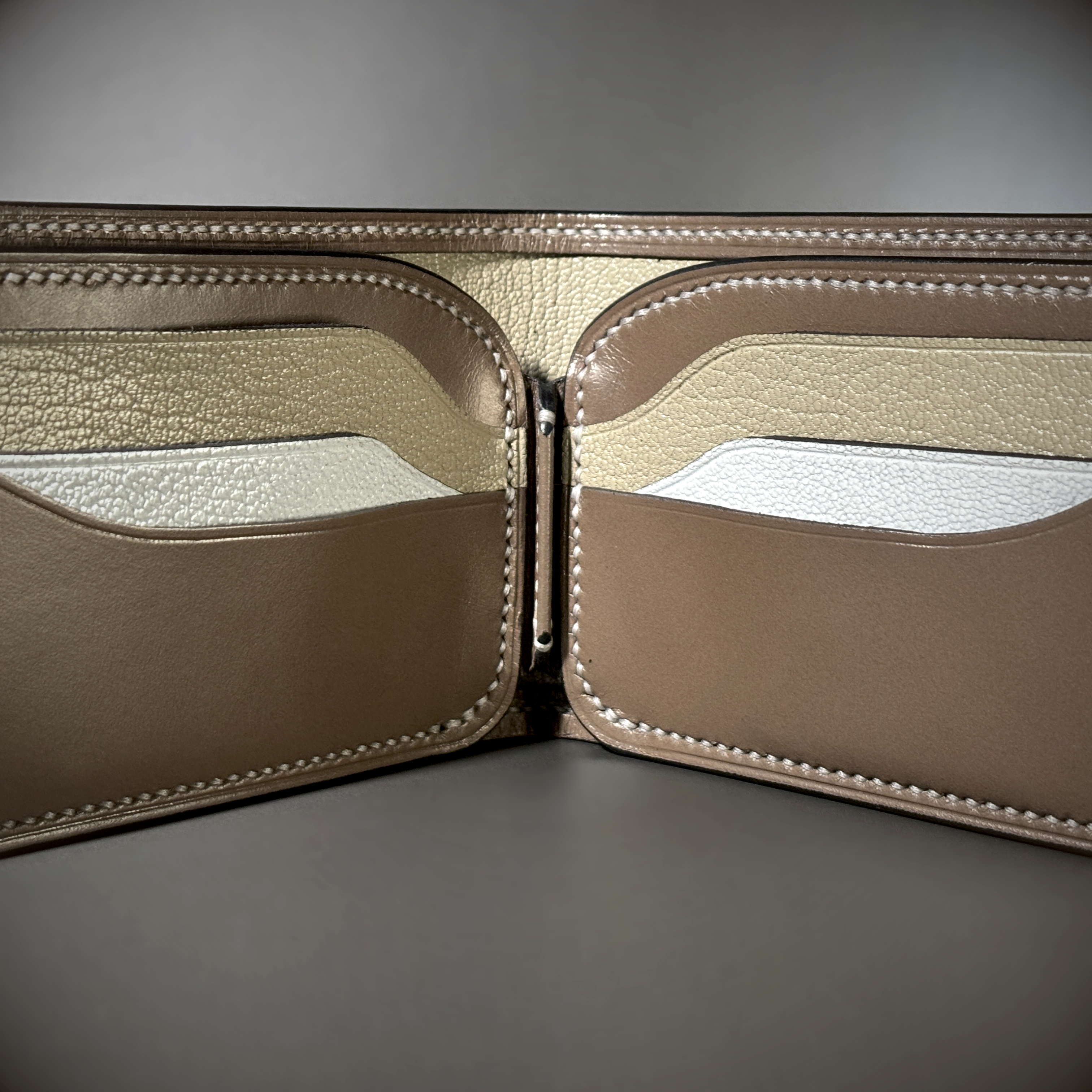 Tan taupe and white bifold wallet with black shell handstitched with white thread detailed view