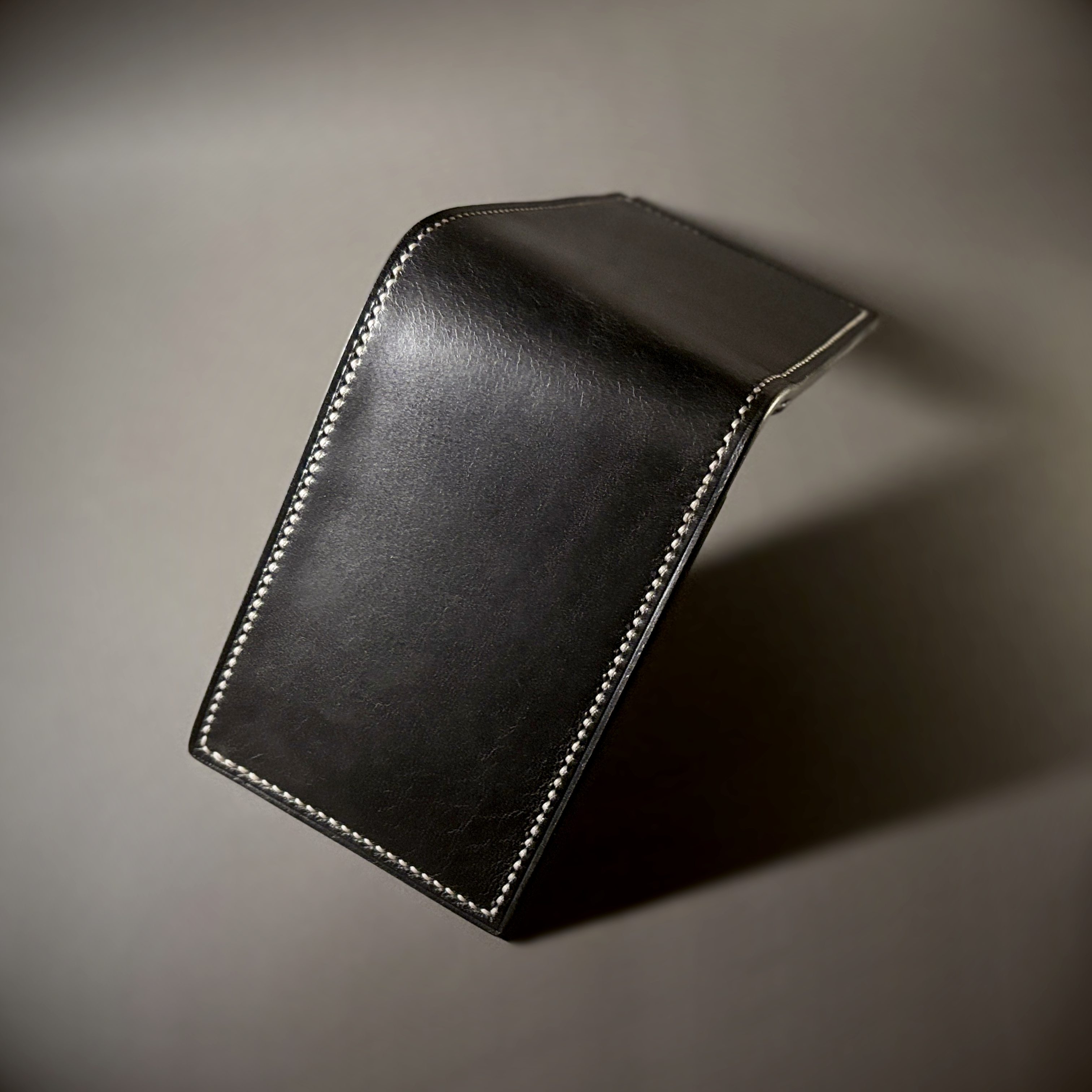 Tan taupe and white bifold wallet with black shell handstitched with white thread exterior shell view