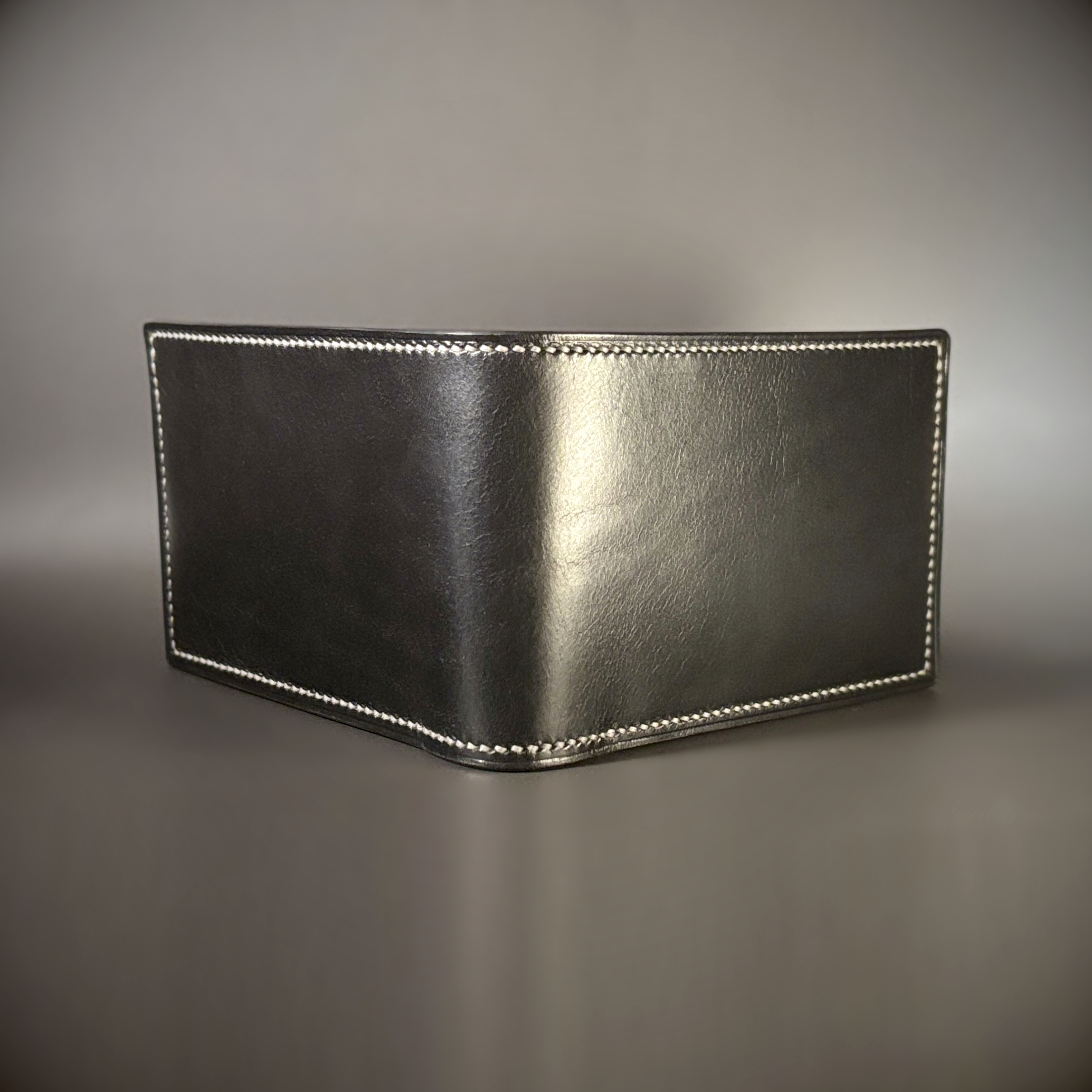 Tan taupe and white bifold wallet with black shell handstitched with white thread exterior shelll view