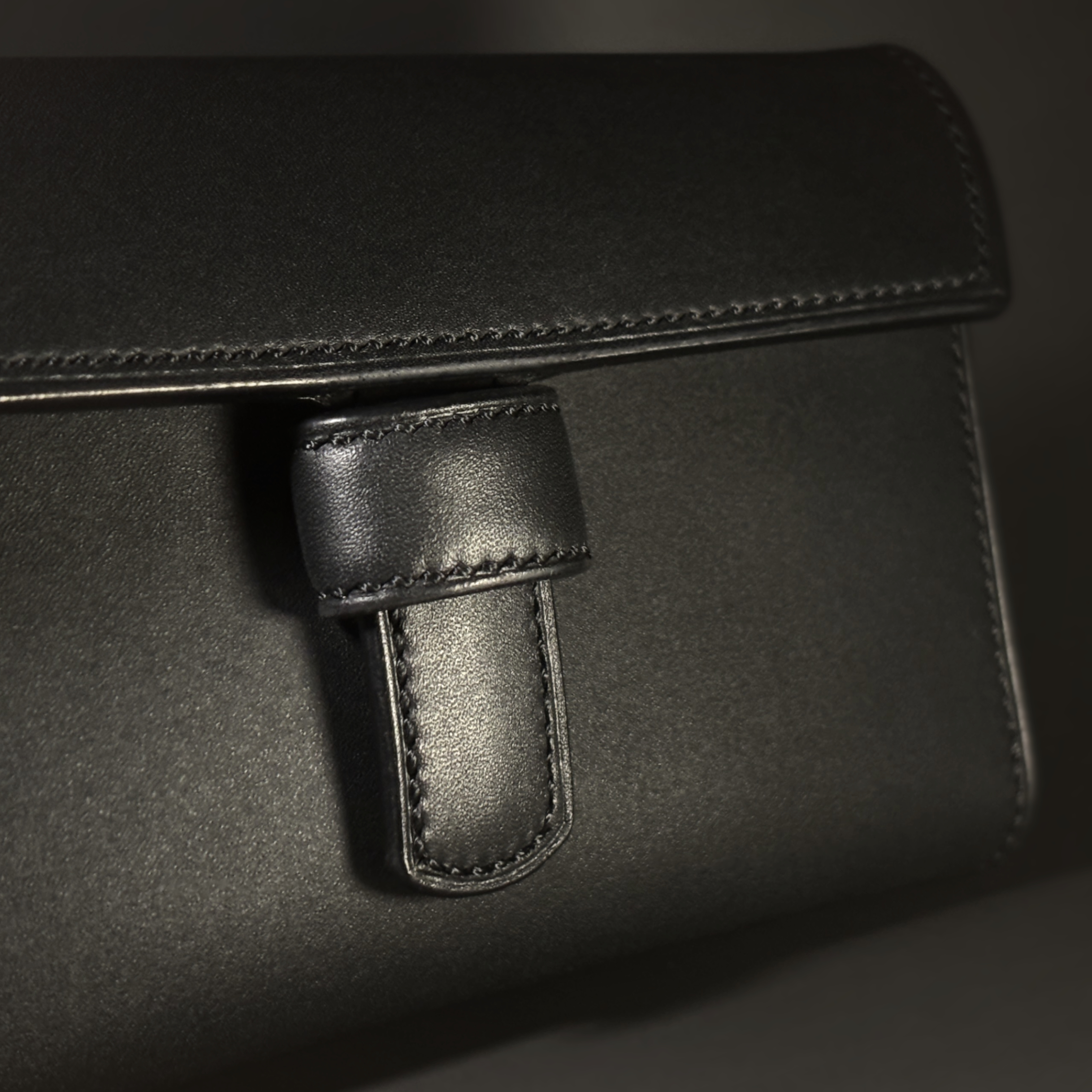 Unique all black hand-stitched tuck strap closure card and cash wallet with money clips exterior shell and tuck closure detailed view