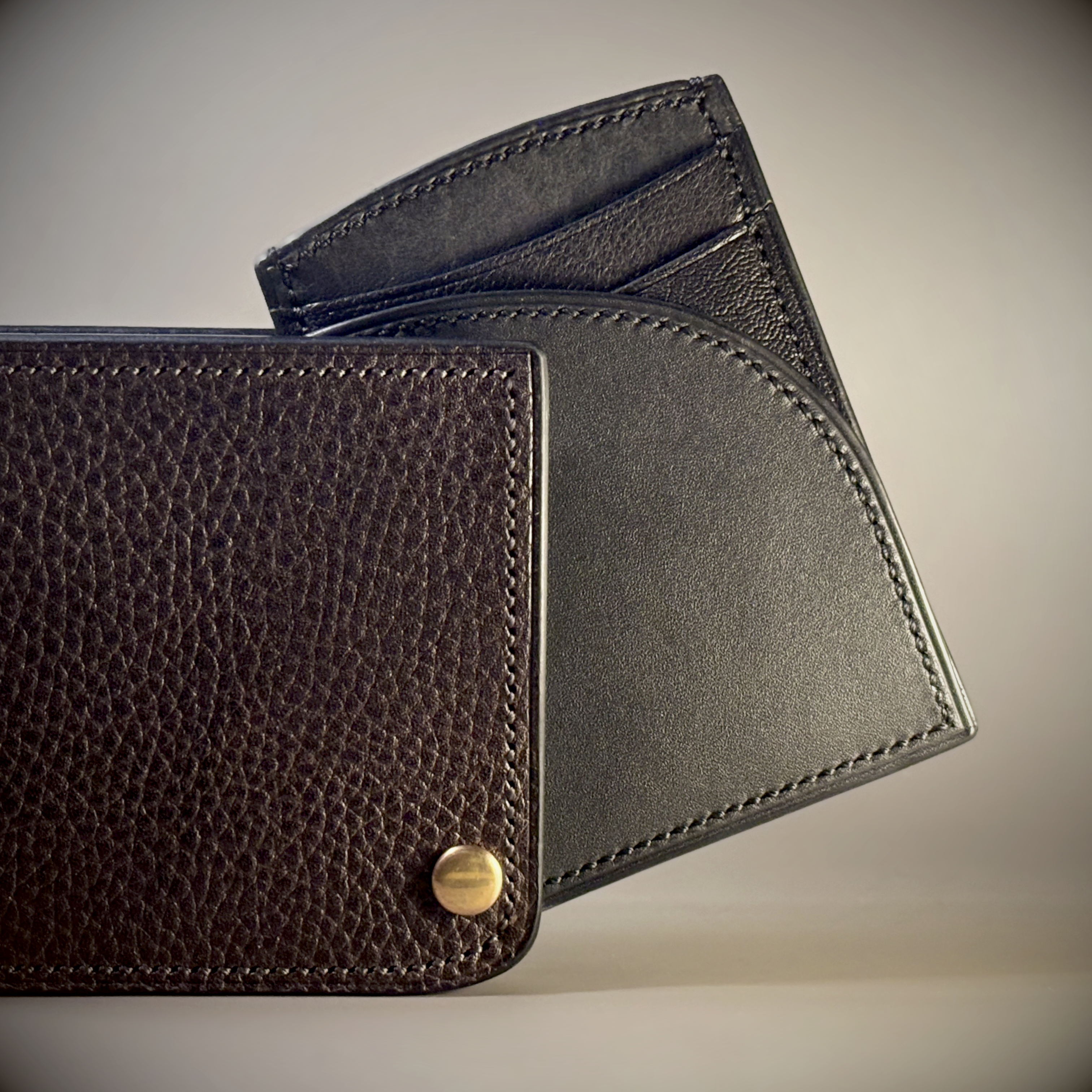 Unique hand-stitched brass hinged brown and black wallet exterior hinge detail view