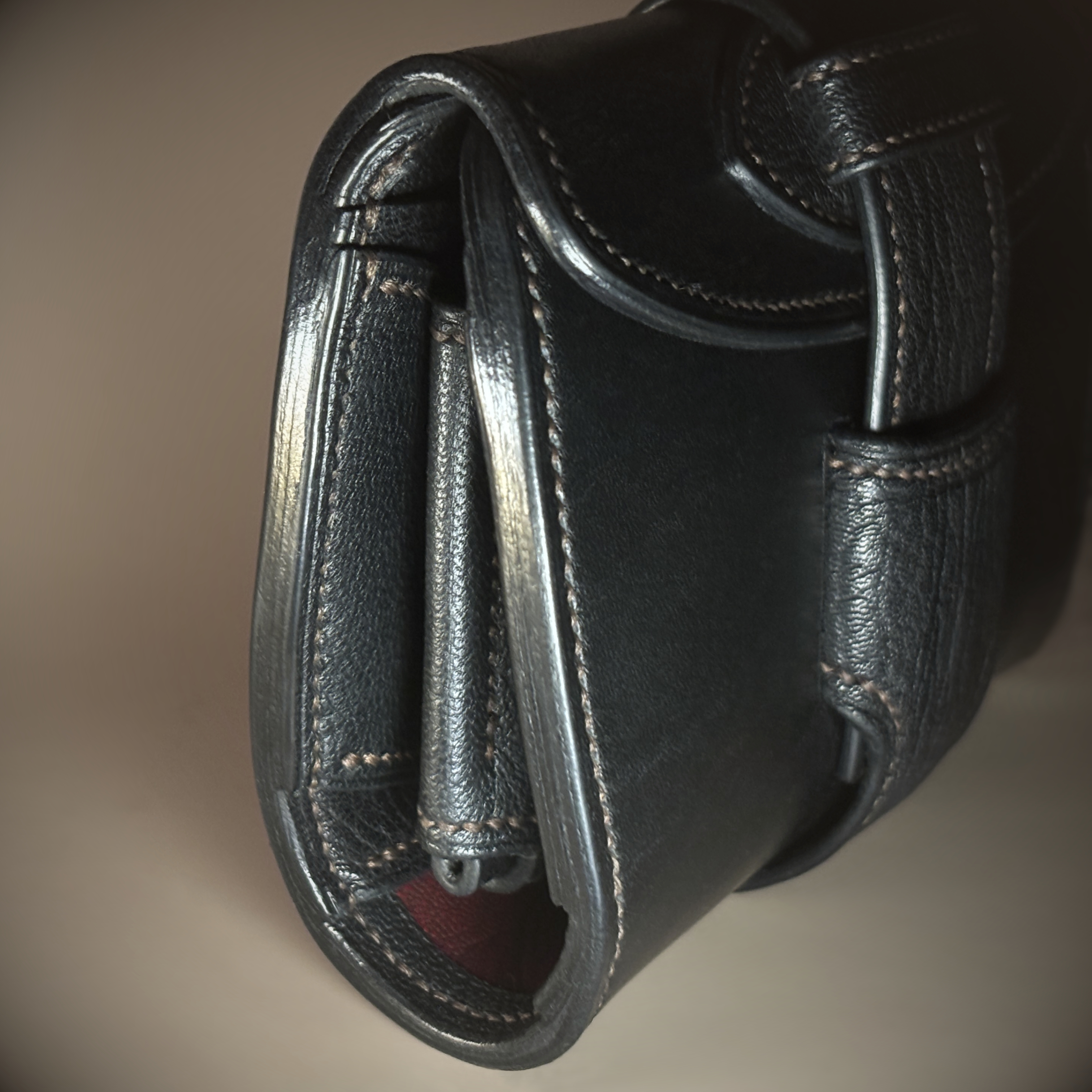 Unique handstitched black with red accent tuck closure purselette side and red accent detail view